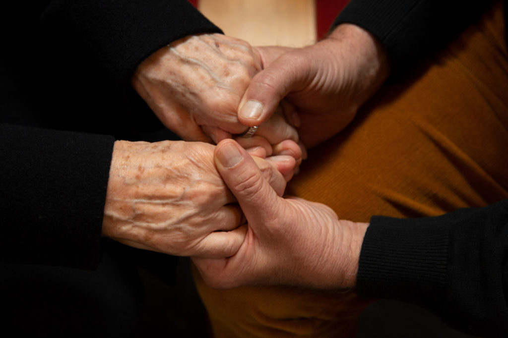 Hände einer alten Person werden gehalten