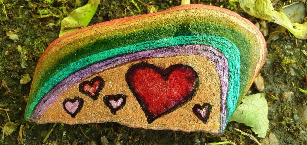 Stein bemalt mit einem Regenbogen und Herzen