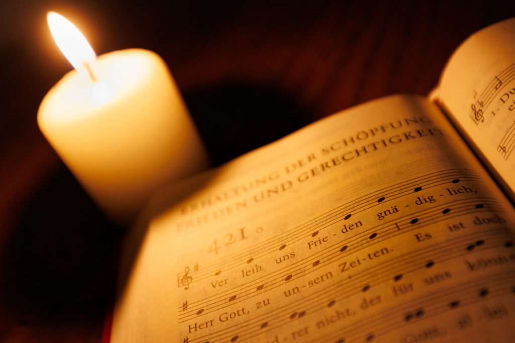 ein Gesangbuch und eine leuchtende Kerze