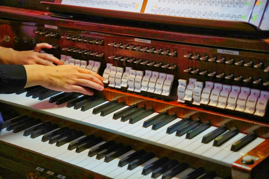 Die Hand des Organisten auf der Orgel.